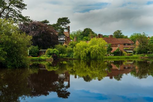 A view of Beaulieu, Brockenhurst across still water on a summer's day