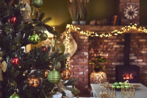 Decorated Christmas tree next to a cosy log burner